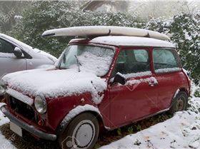 12616278-surfboard-on-a-car-roof-covered-by-snow-Stock-Photo