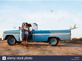 portrait-of-young-female-surfer-leaning-on-pick-up-truck-door-leucadia-E8AMY8