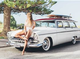 Portia-leaning-against-classic-surf-car-with-surfboard-on-roof